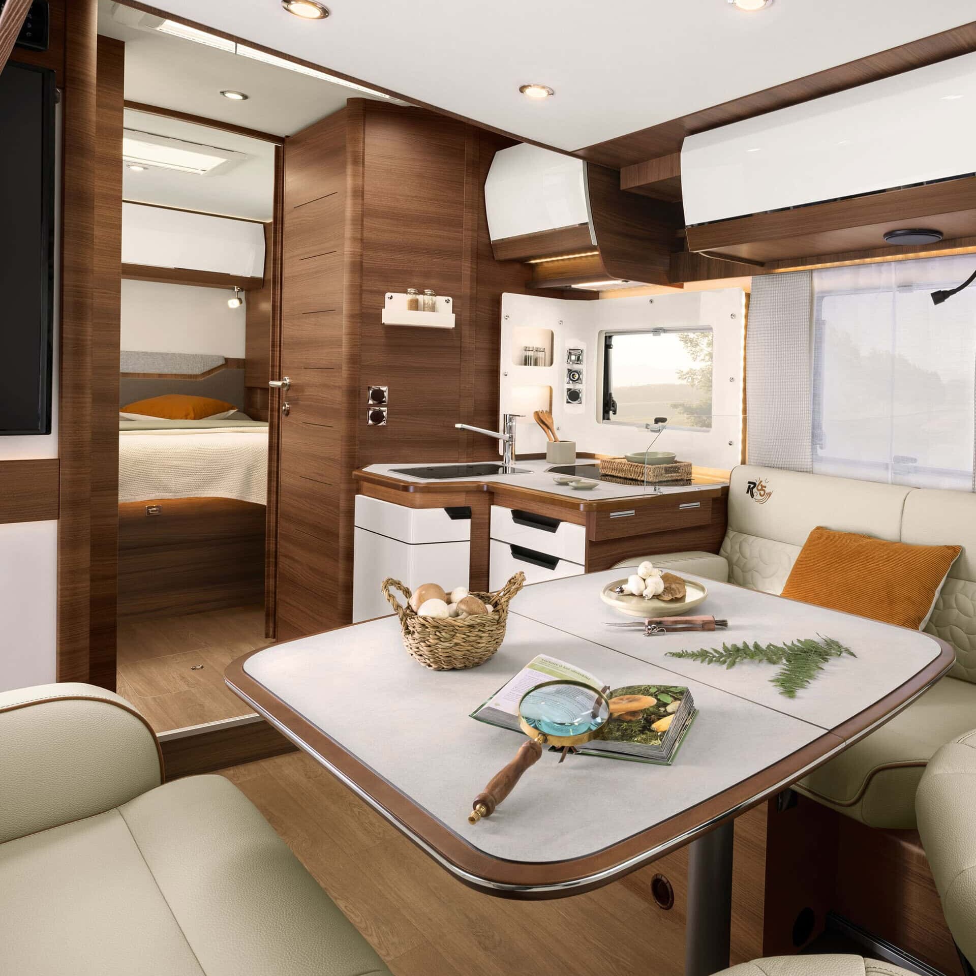 Bild över inrednign i en halvintegrerad husbil med face-to-face soffa, mörk och ljus inredning