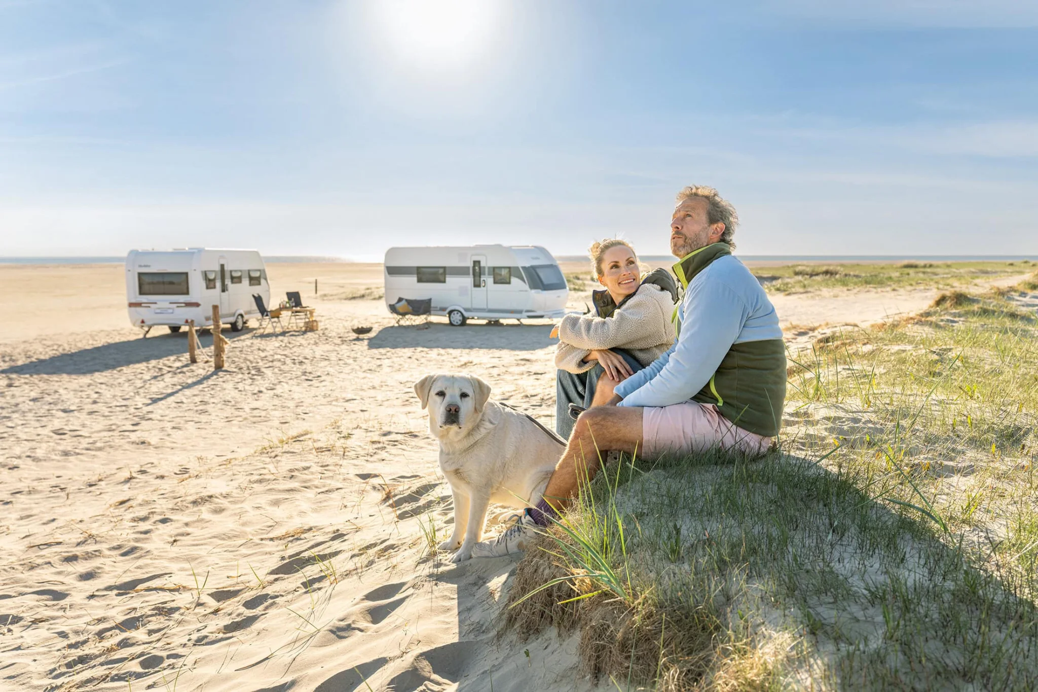 Man och kvinna med hund vid husvagn på strand