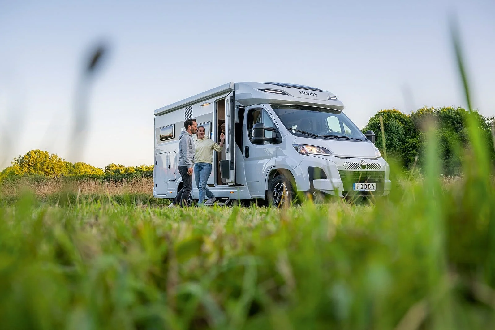 Hobby Ontour C 680, husbilsäventyr utomhus på äng med man och kvinna